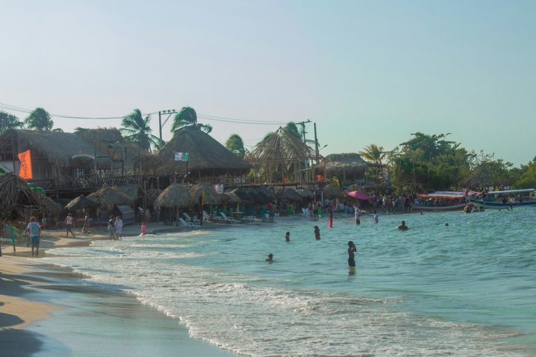 Playa con personas y edificios al fondo en la costa del Caribe
